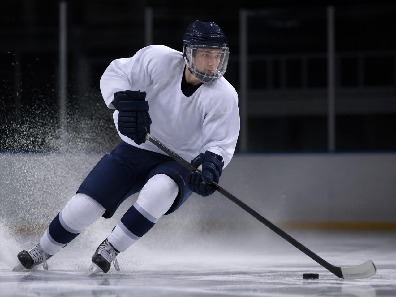 Ice hockey player carving on the ice wearing a clear helmet visor